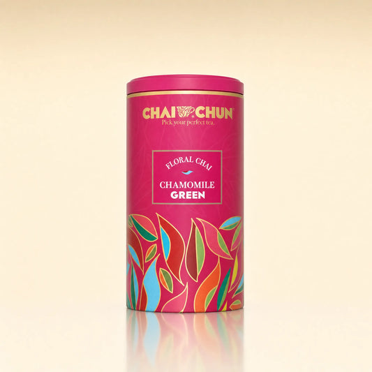 A cylindrical pink tea tin labeled CHAI CHUN Floral Chay Chamomile Green, featuring colorful stylized leaf illustrations on a warm cream background.