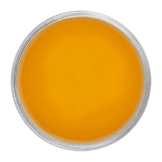 A top-down view of a circular clear container filled with a vibrant orange-yellow gel or cream, set against a solid white background.