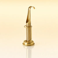 Signature Grip Infuser – Gold-toned stainless steel upright tea infuser with a hook-shaped handle, cylindrical mesh body, and a circular base stand, photographed on a warm cream background with a soft reflection below.