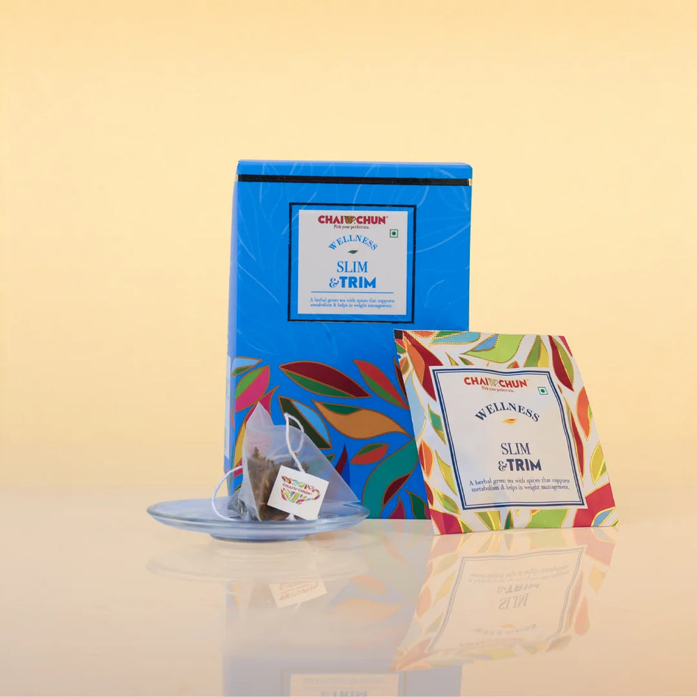 A blue tea box labeled CHAI CHUN Slim & Trim stands on a reflective surface next to a single tea bag on a saucer and a smaller front-facing package card. The background is a soft warm beige gradient.
