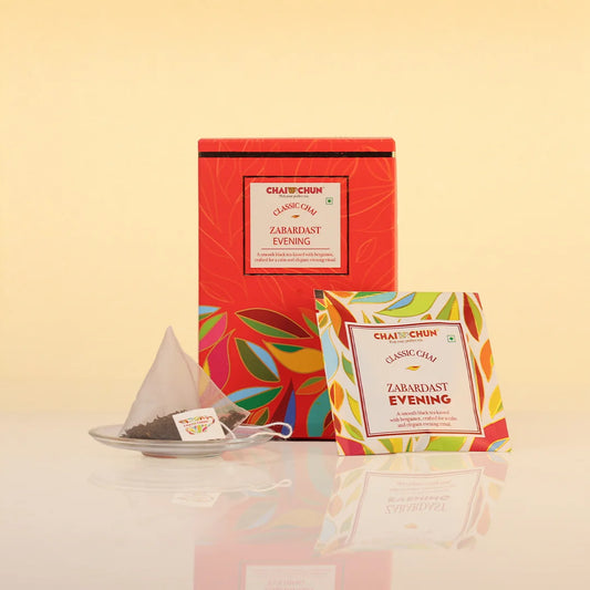zabardast-evening - A tea gift set from Chai Chai featuring a red box, a single tea bag on a small saucer, and a single tea bag packet labeled 'Classic Chai Zambast Evening' against a warm beige background.
